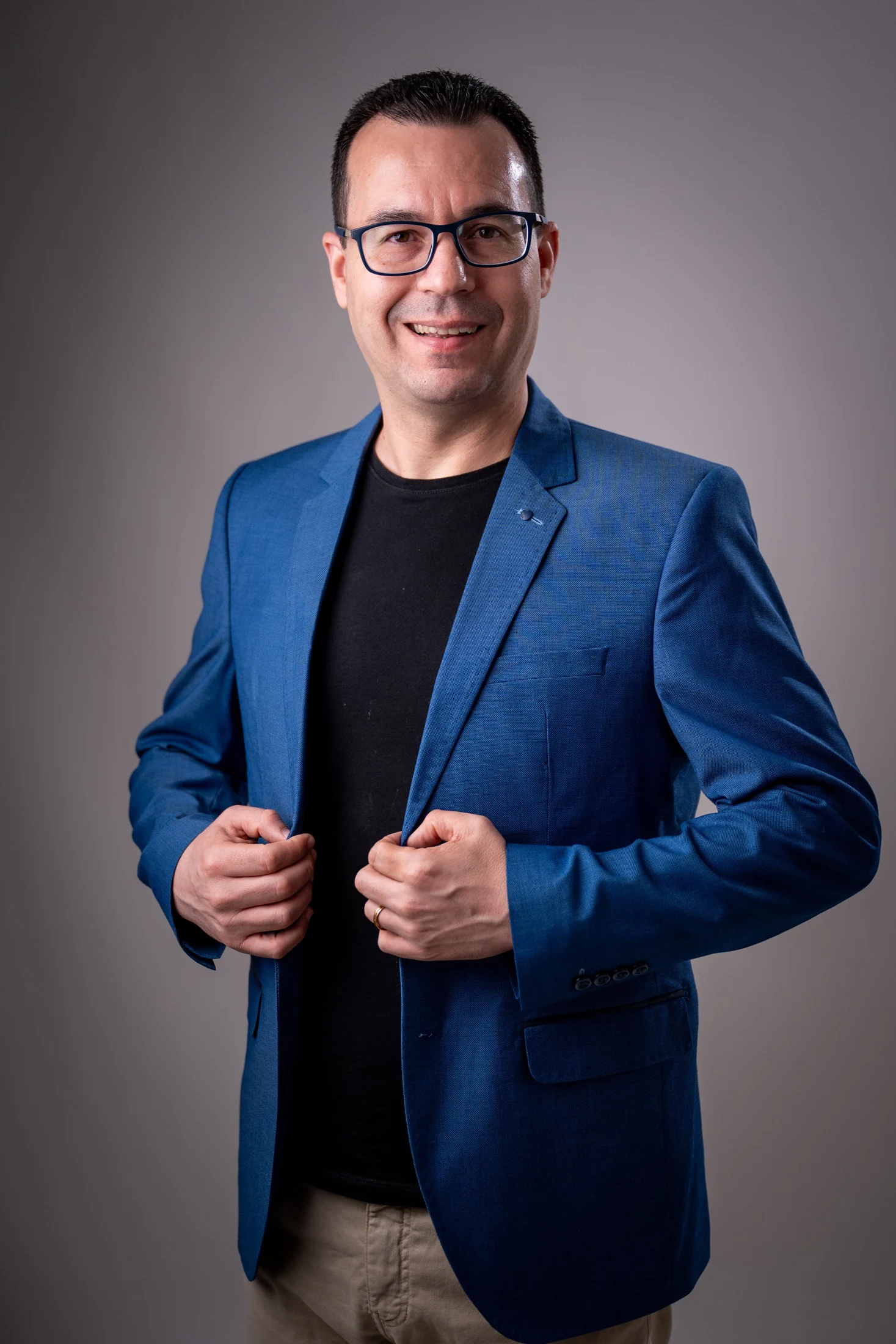 Gustavo Isaias sorri em retrato profissional, de blazer azul